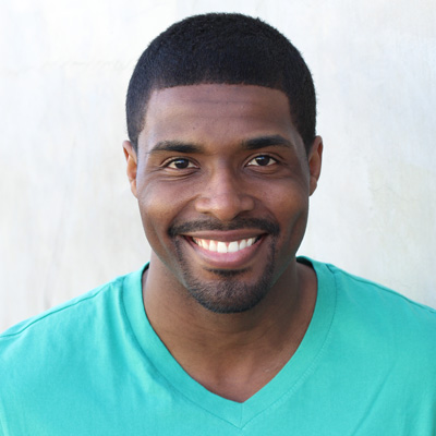 An elderly couple sharing a warm embrace, smiling broadly at the camera against a backdrop of natural landscape.