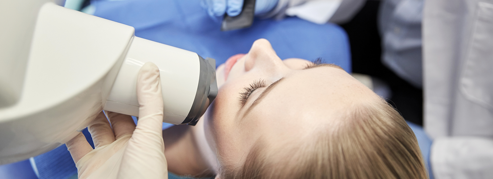 A woman receiving dental care, viewed through a dental microscope by a dentist.