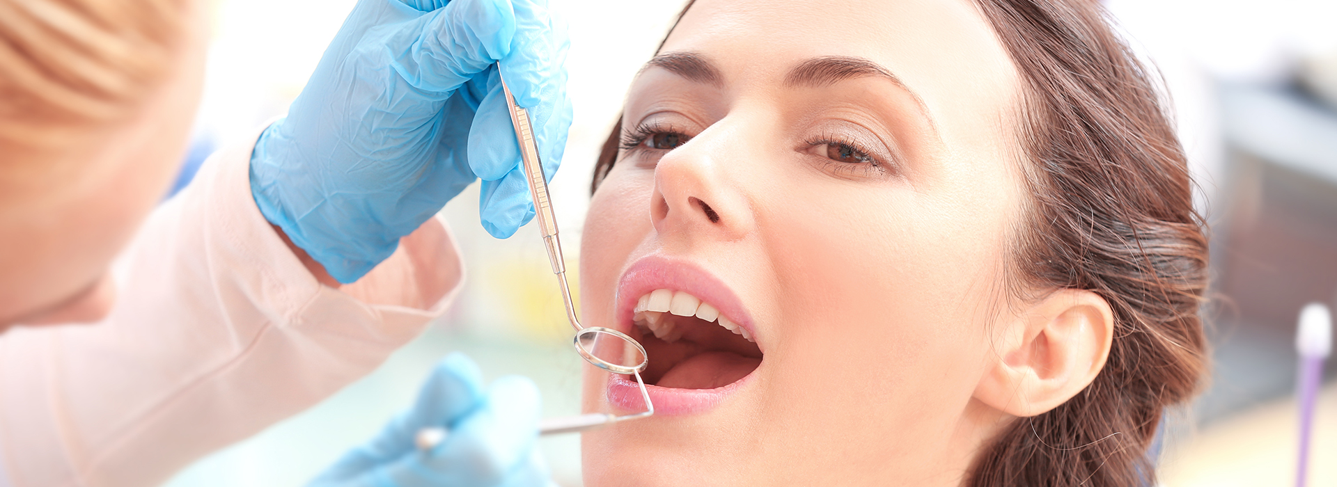 A woman receiving dental care, with a dentist using tools to examine her teeth.