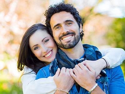 A man and a woman, both smiling, posing together for a portrait.